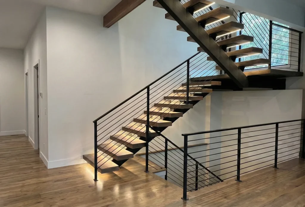 Custom mono stringer floating stairs in a Seattle home with wood treads, horizontal black metal railings, and integrated under-tread LED lighting