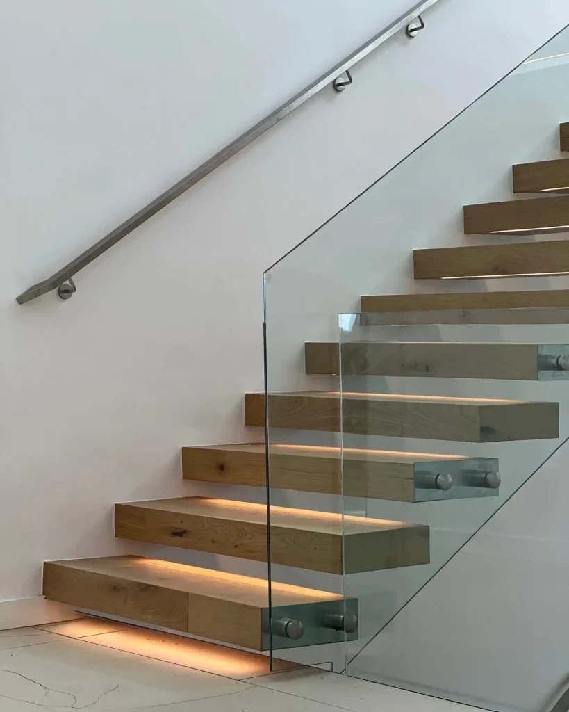 Cantilever floating stairs with wood treads, frameless glass railings, and LED under-tread lighting in a Seattle home